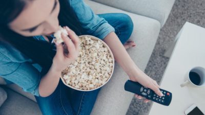 Woman eating popcorn and watching tv