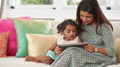 Little daughter and her mother watching educational program on digital tablet