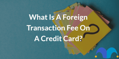 Post-it notes with question mark with the text “What is a foreign transaction fee on a credit card?” and The Motley Fool jester cap logo